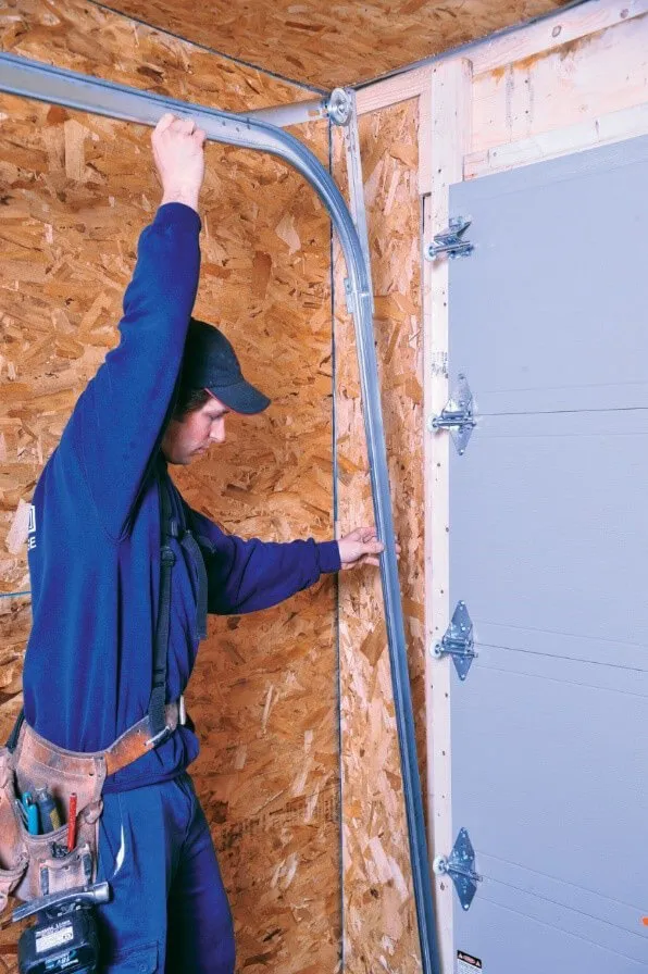 Installateur en train d'installer les rails d'une porte de garage