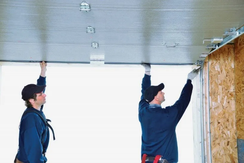 Deux installateurs en train d'installer une porte de garage